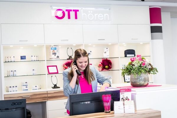 Freundliche Mitarbeiterin im Hörakustik-Fachgeschäft Ott hören am Empfangstresen.